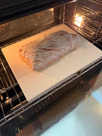 Loaf of bread baking inside an oven on a white sheet of paper.