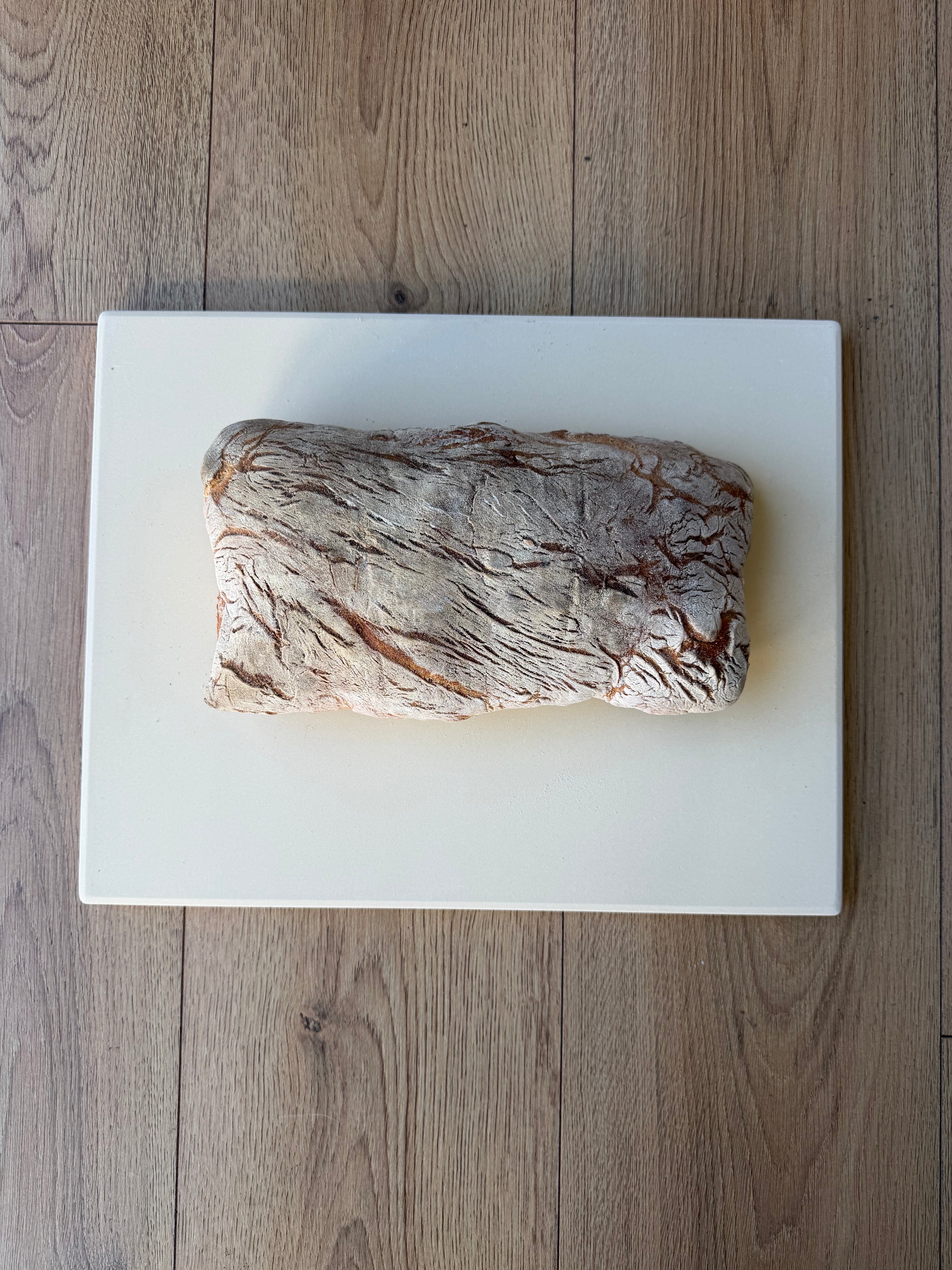 Loaf of bread on a white marble slab with a wooden floor background
