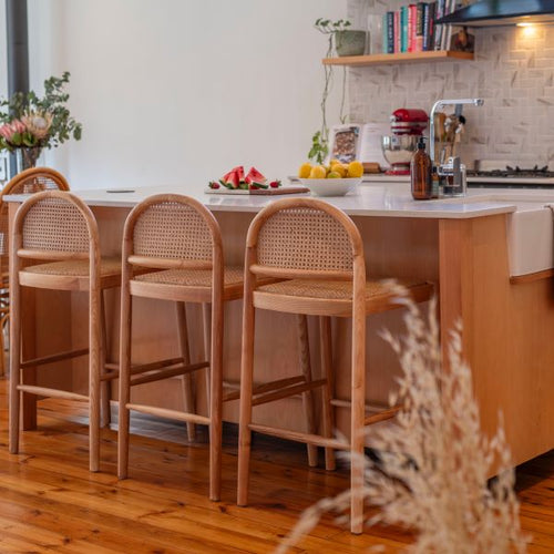 Kitchen with wooden island and bar stools, fruit on the counter