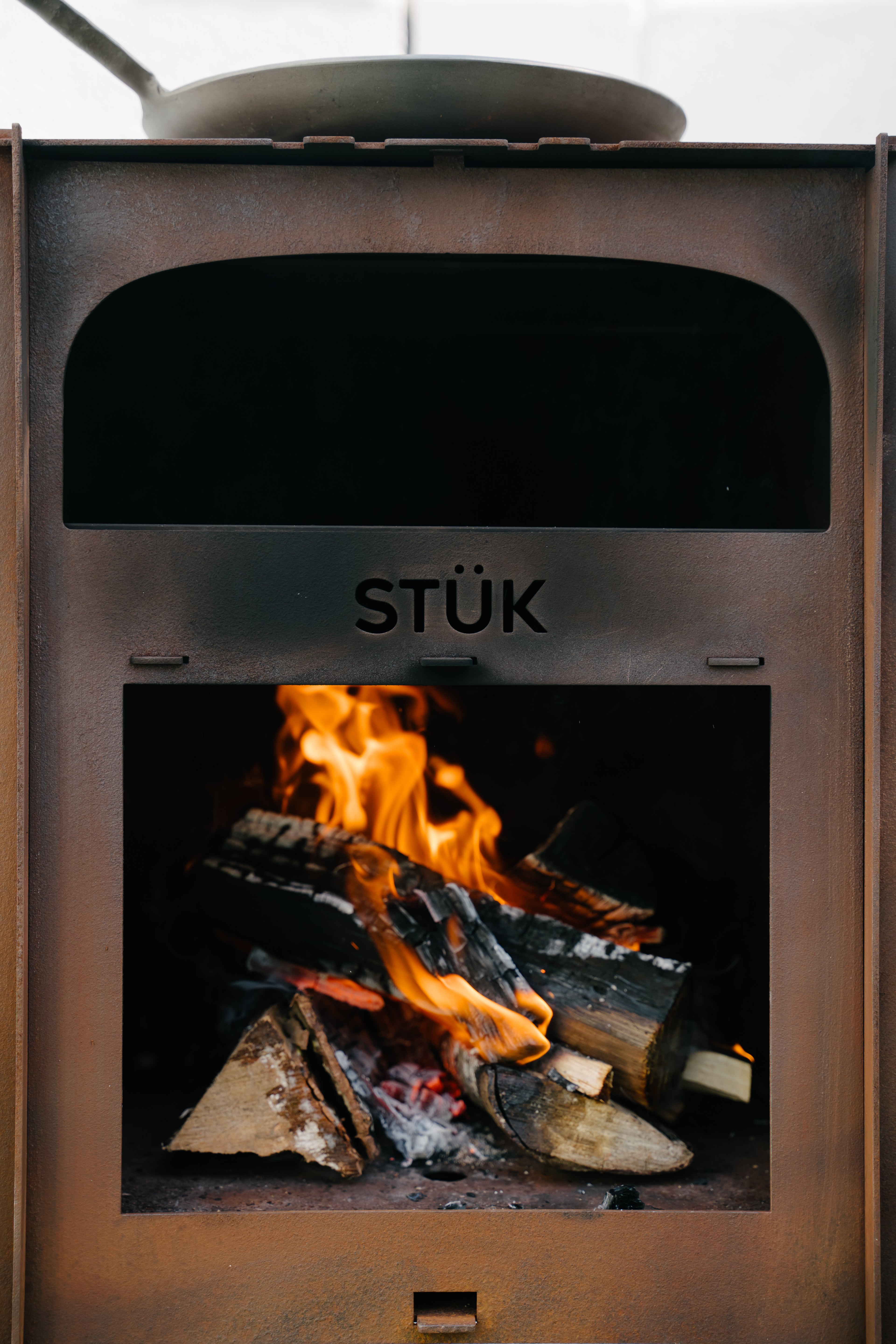 Wood-burning stove with flames inside, branded 'STÜk'.