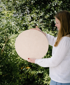 Person holding a large spherical object outdoors with greenery in the background