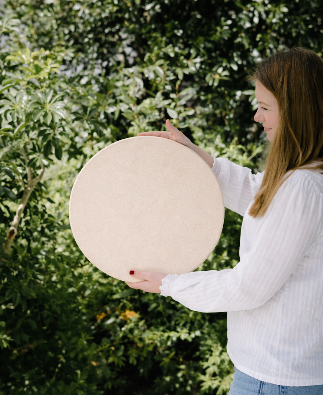 Person holding a large spherical object outdoors with greenery in the background