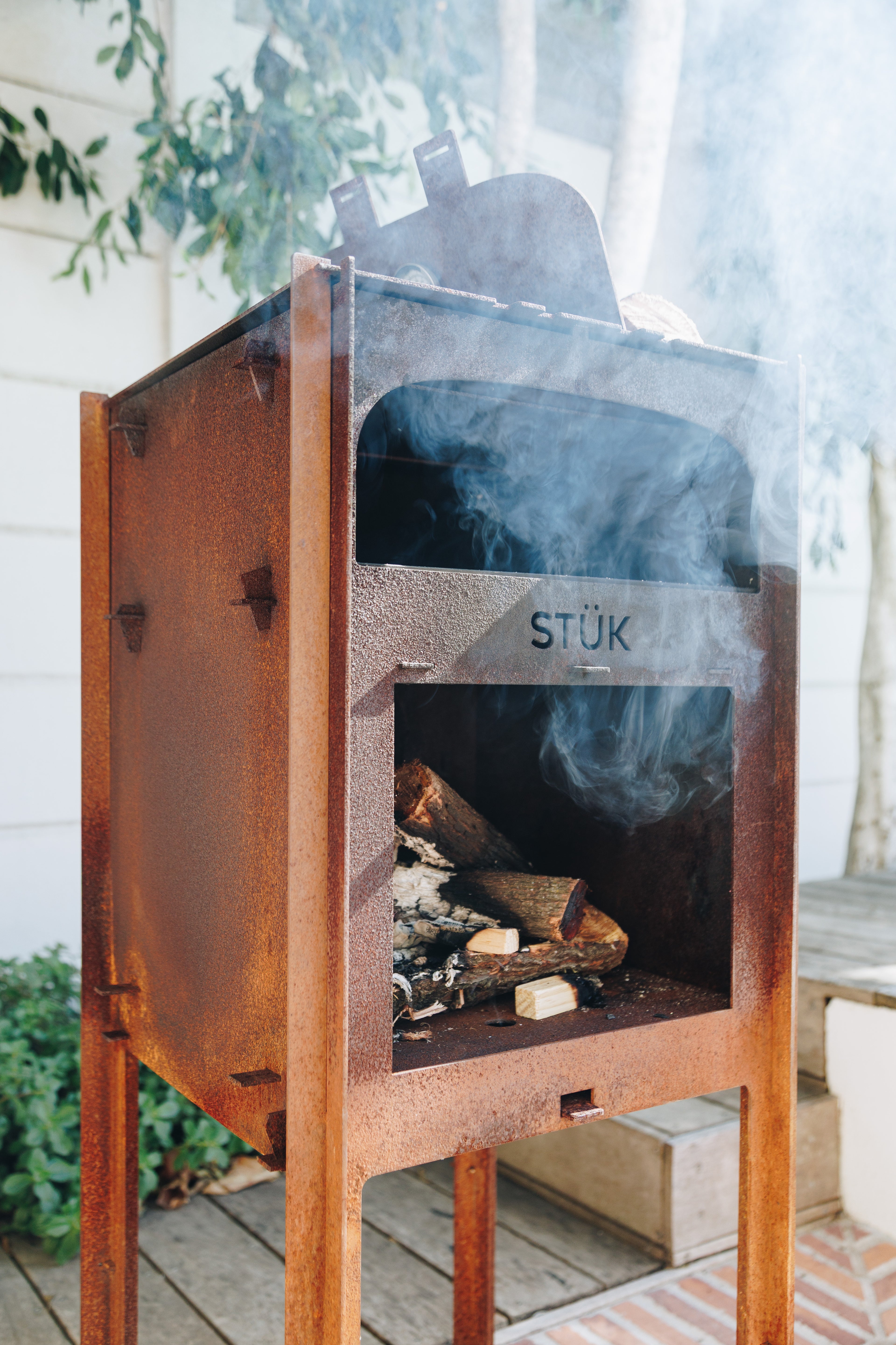 Wood-burning stove with 'STÜk' branding on a wooden deck.