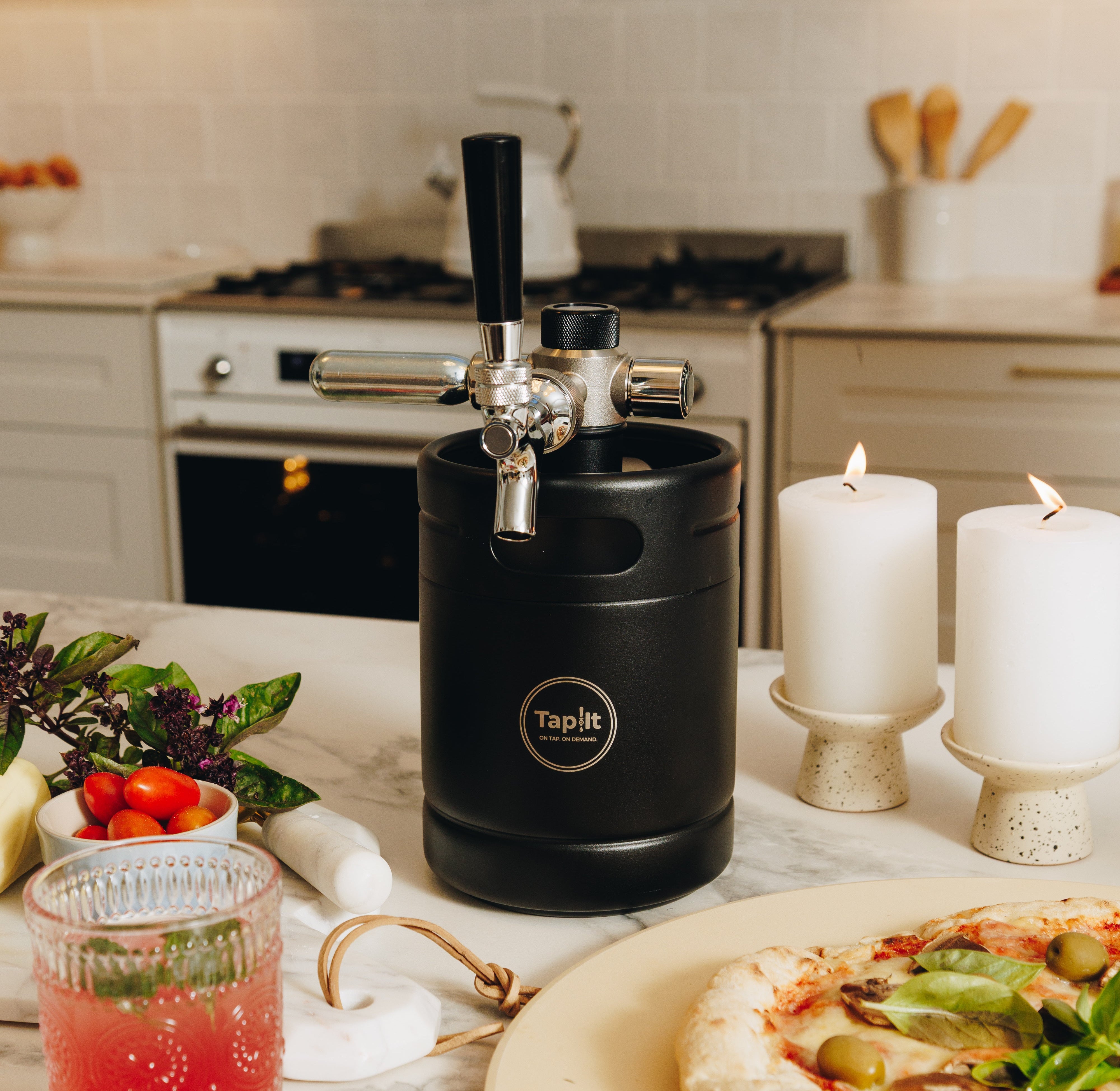 Black beer keg on a kitchen counter with pizza and drinks
