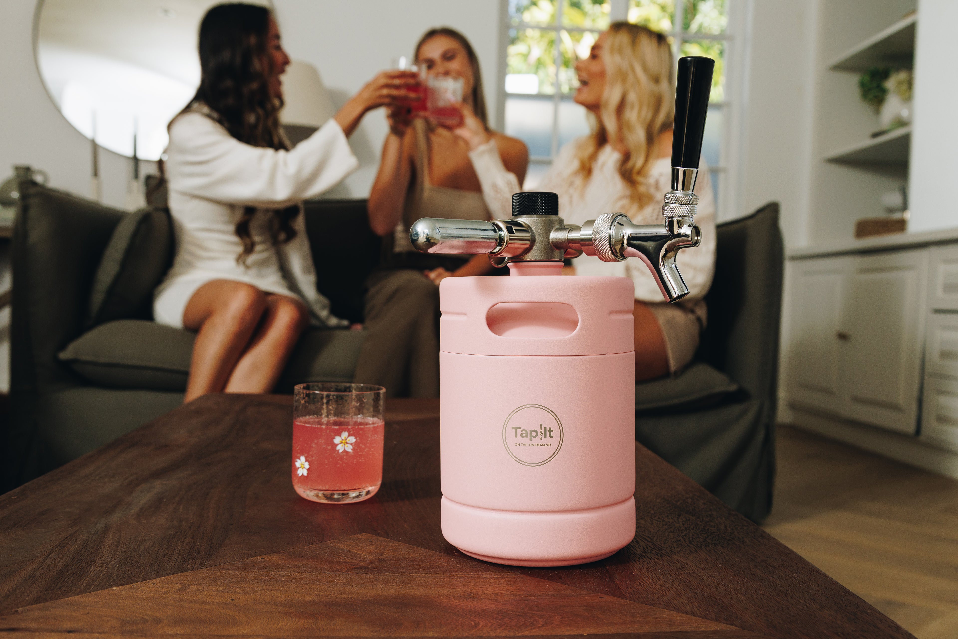 Pink keg with 'Top It' branding on a table, surrounded by people in a casual setting.