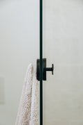 White towel hanging on a black towel rack against a light gray wall