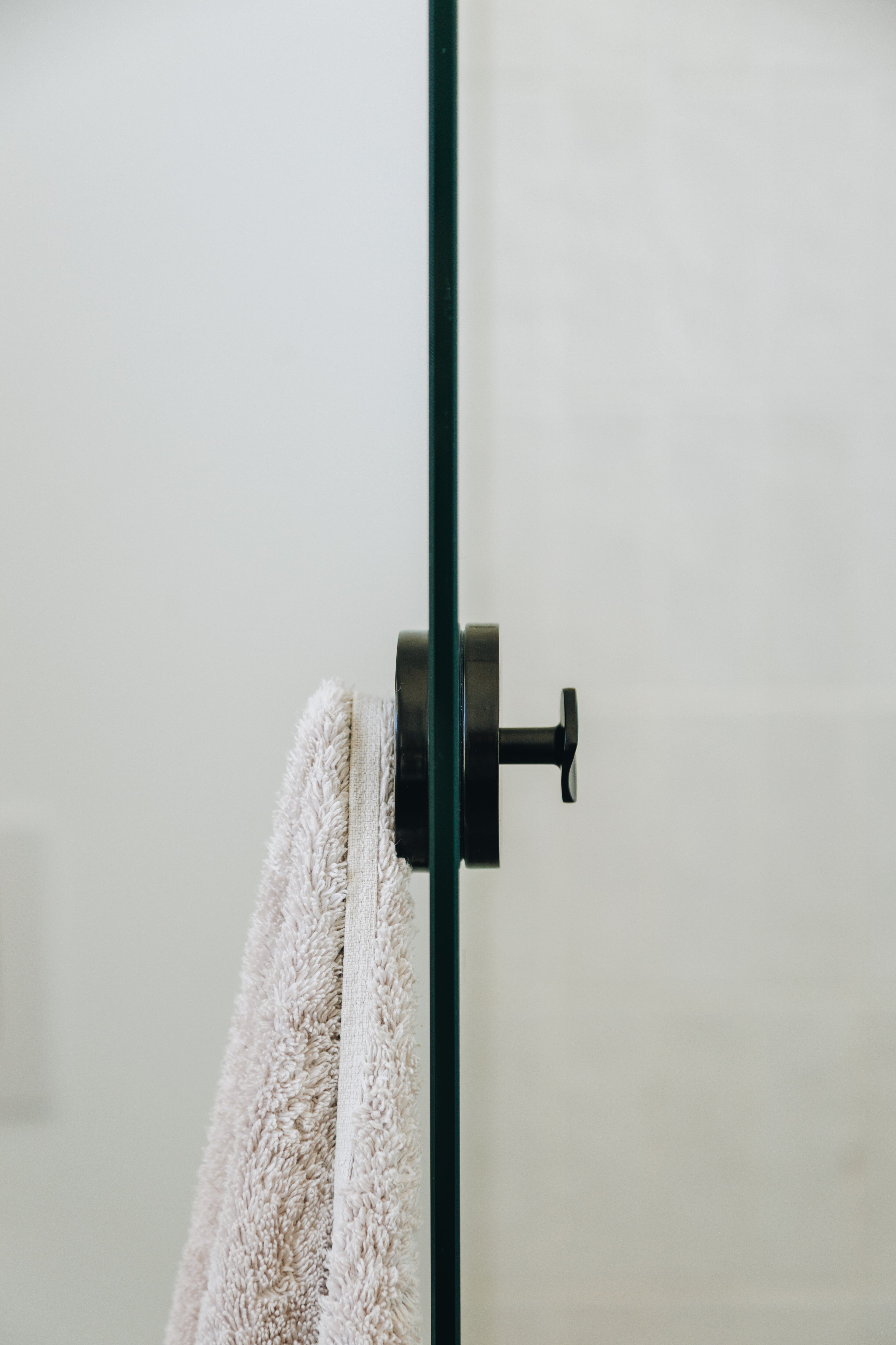 White towel hanging on a black towel rack against a light gray wall